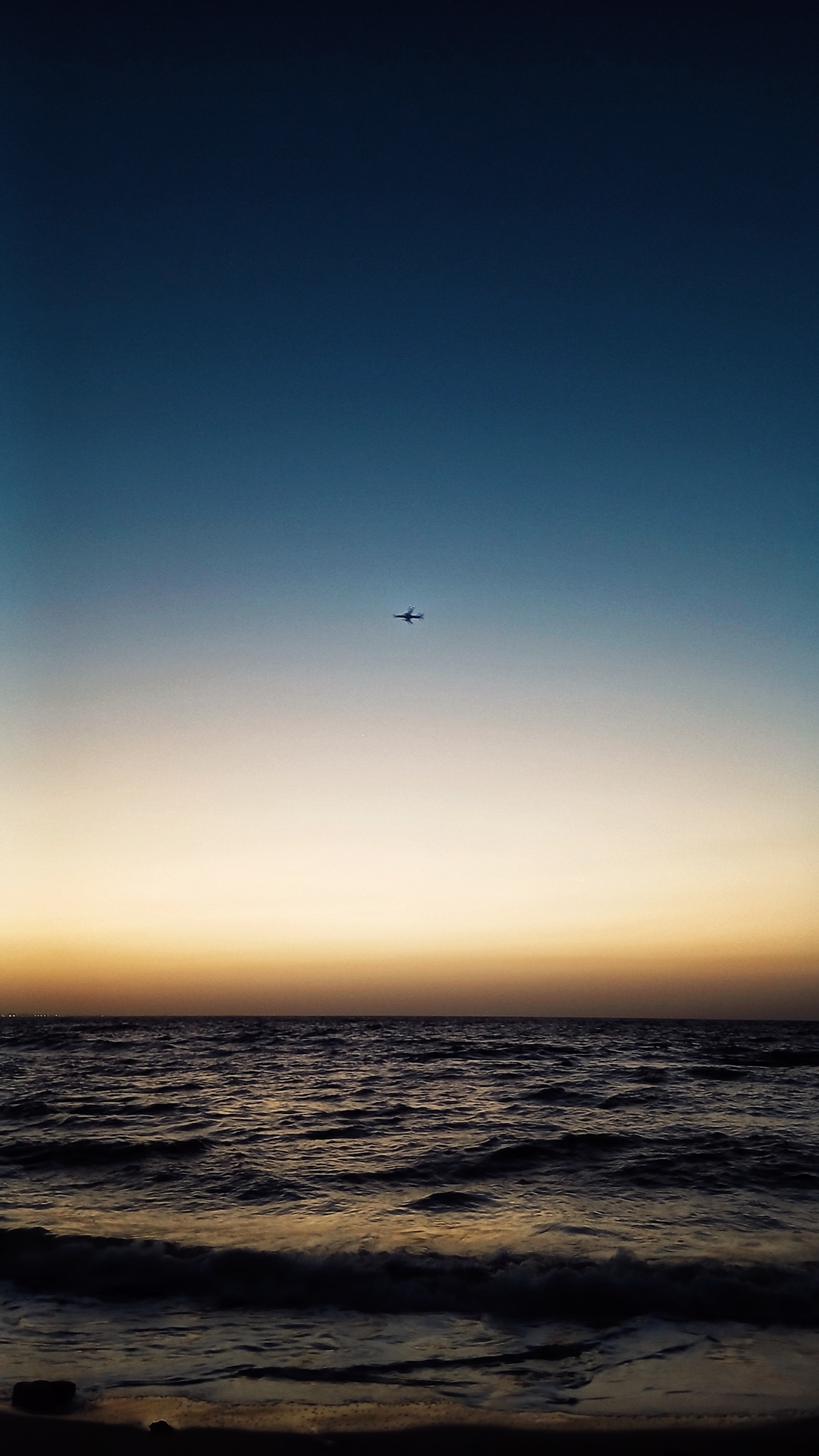 Aircraft silhouette over the ocean at dusk