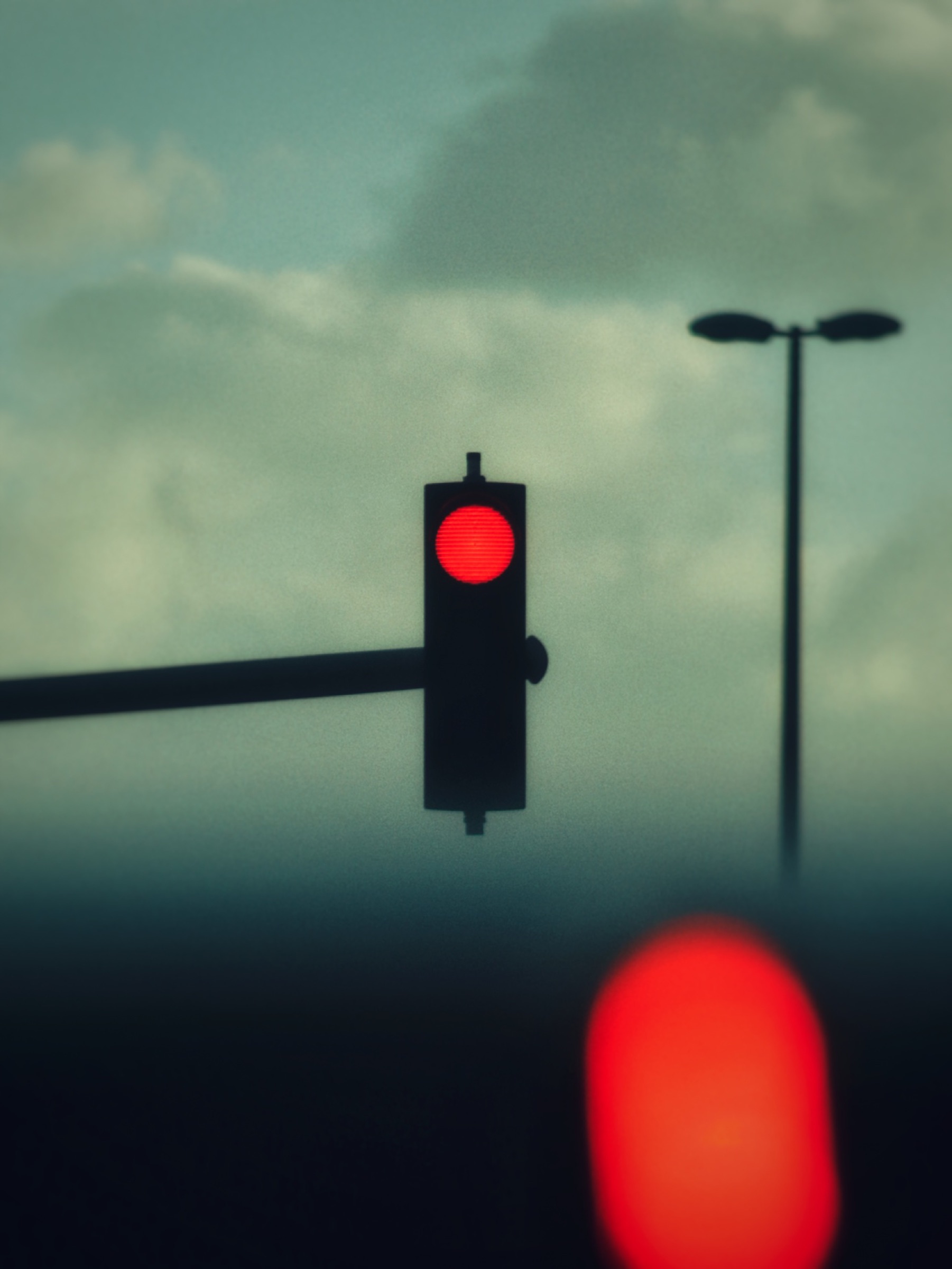 Red traffic light against a moody cloudy sky