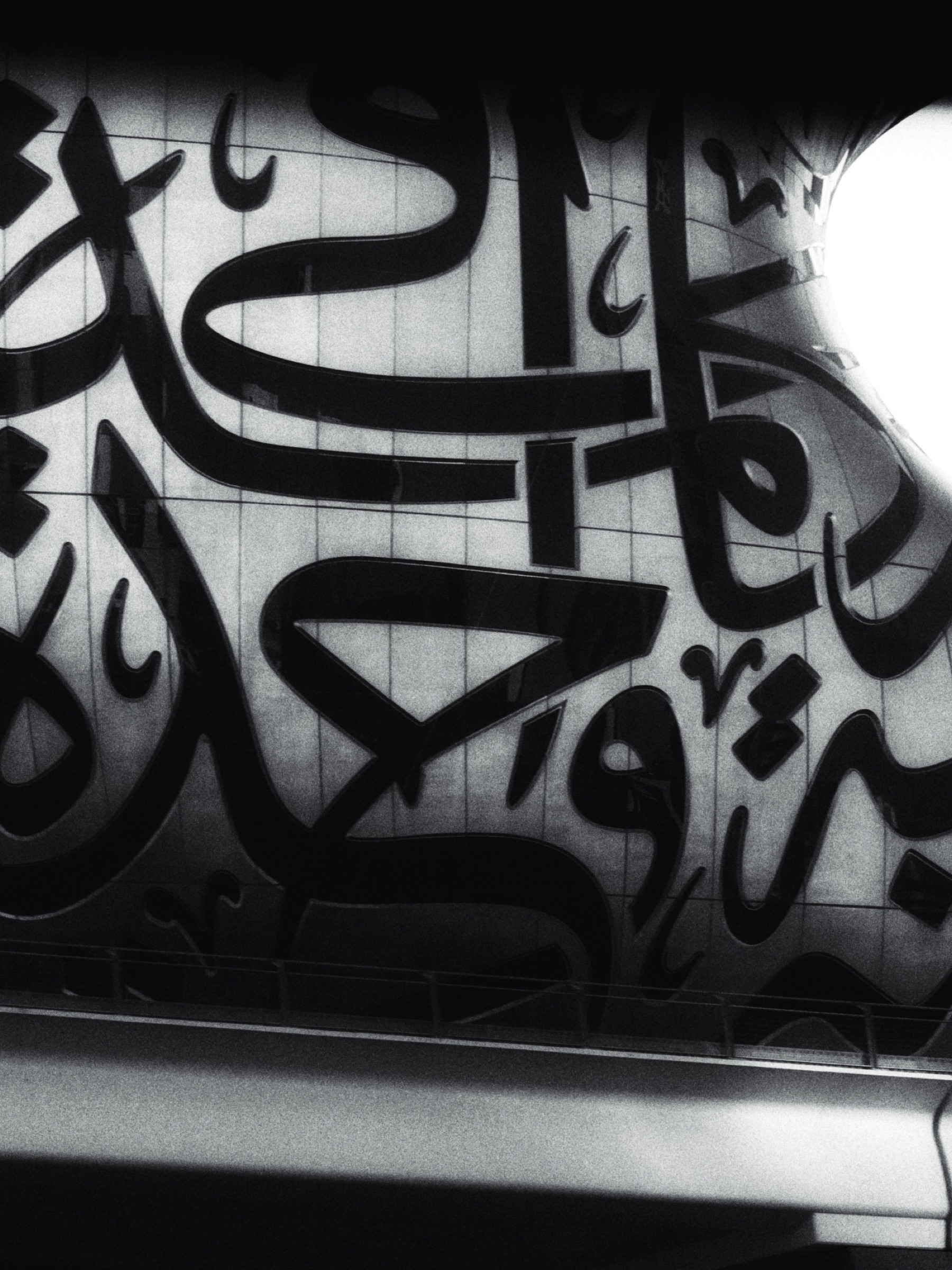 Arabic calligraphy sculpture on a building facade, black and white