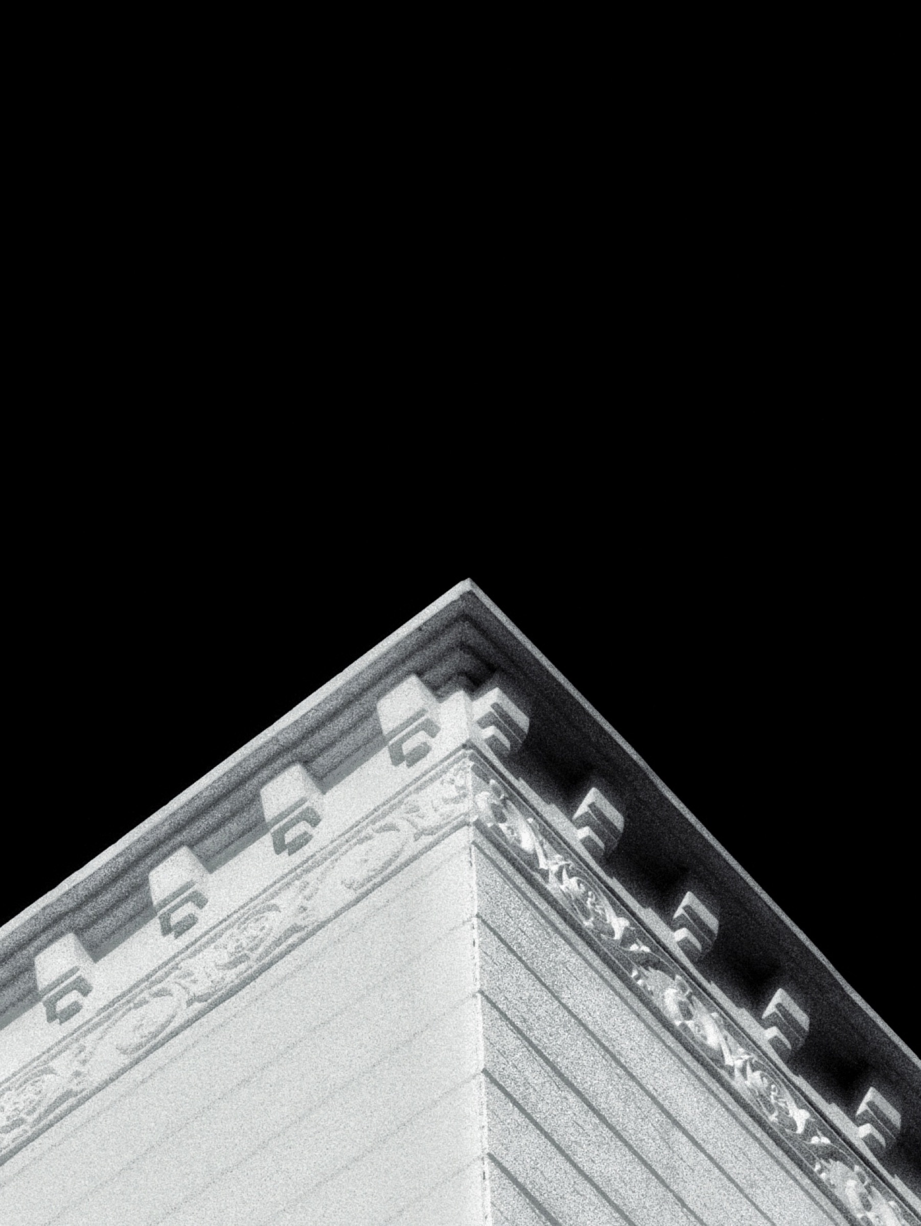 Black and white study of a building cornice against the sky