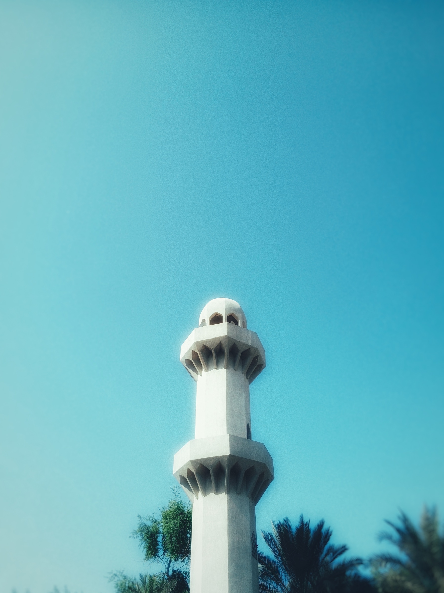 Minimalist white minaret against a clear blue sky