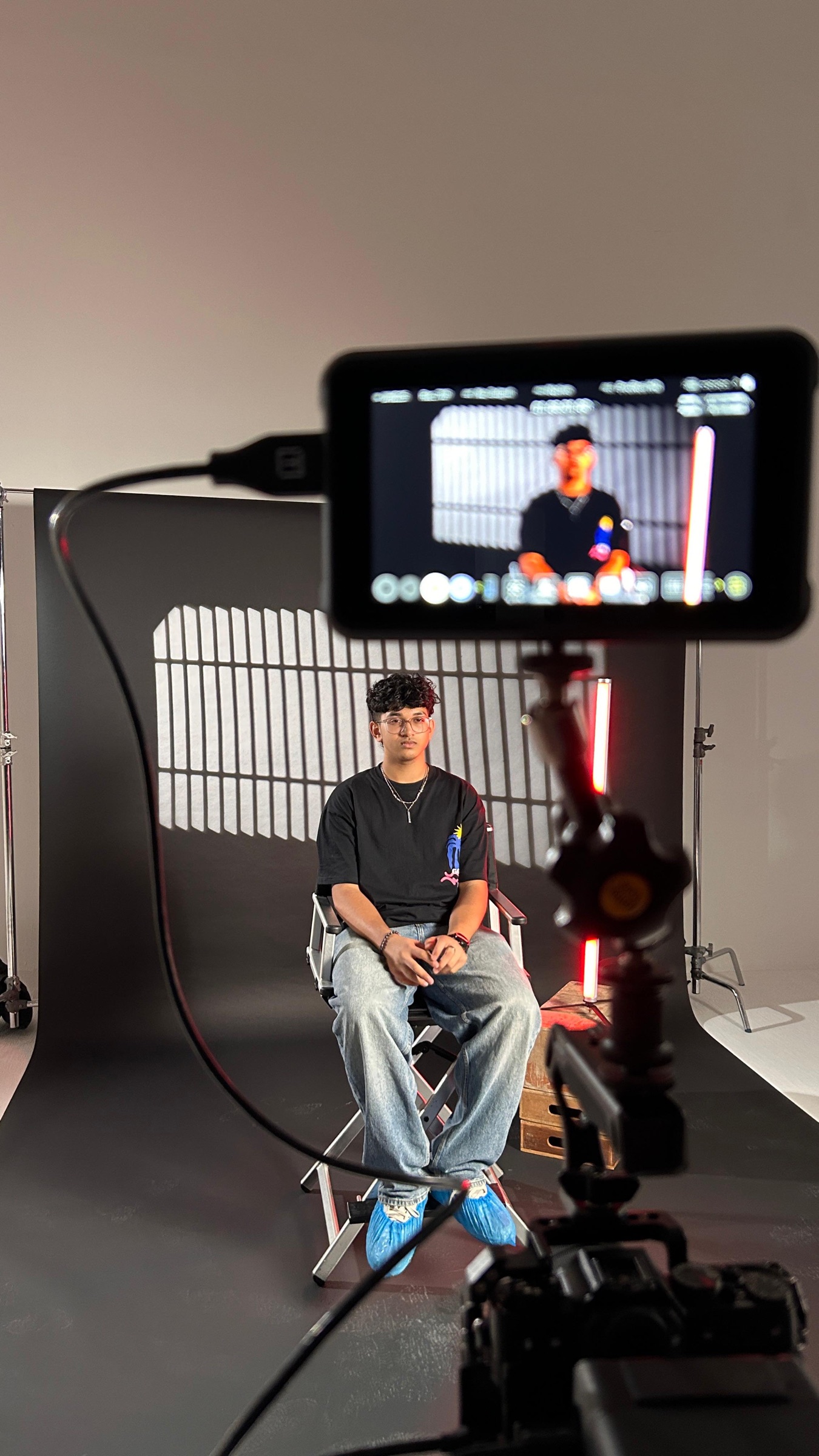 Raashid Ambel on set in the director's chair, monitor showing the live camera feed